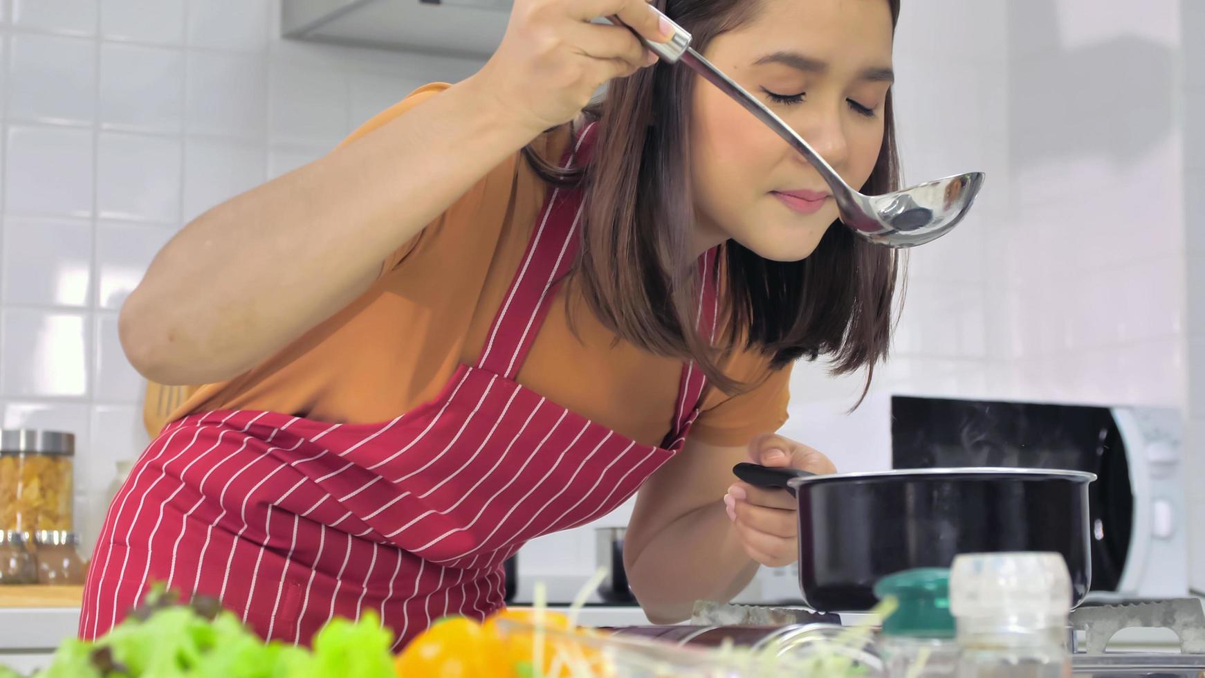 ung asiatisk kvinna matlagning i kök på Hem. foto