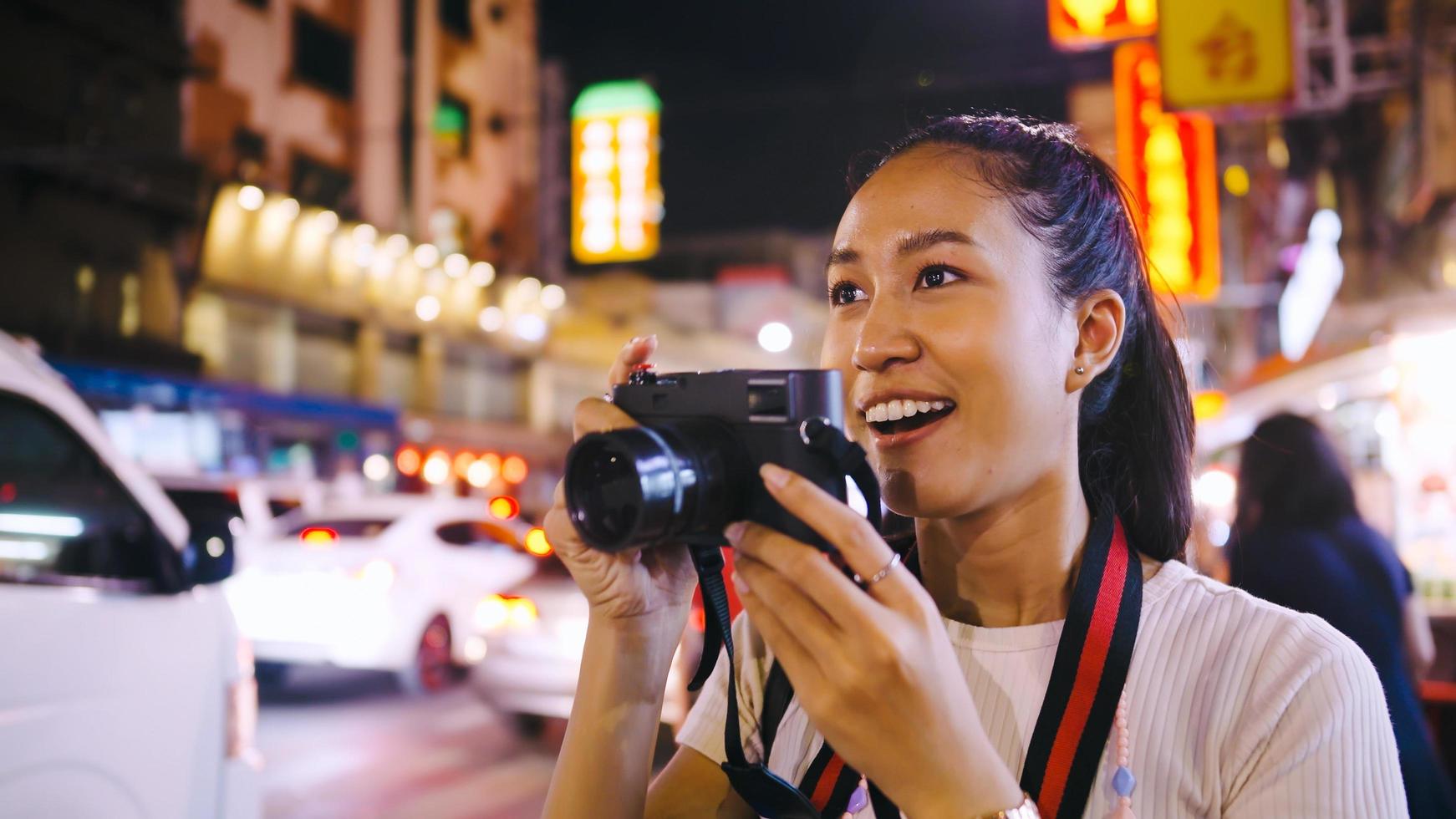 ett asiatisk kvinna turist åtnjuter tar foton av de natt se av Yaowarat väg eller china i Bangkok, thailand.