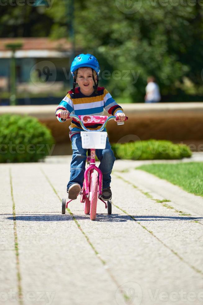 Lycklig pojke inlärning till rida hans först cykel foto