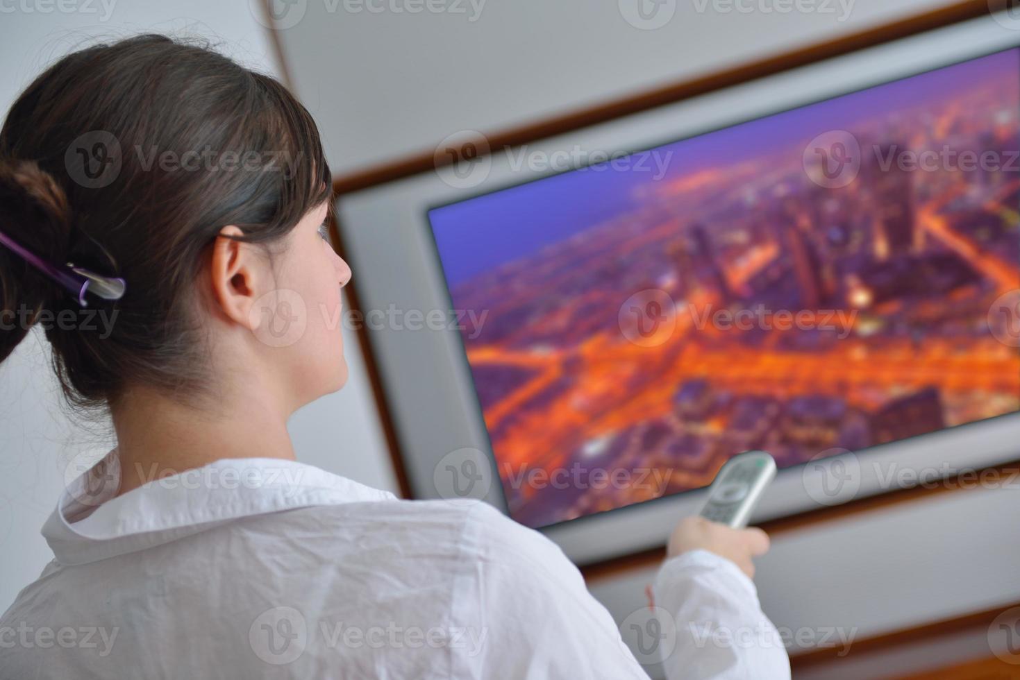 ung kvinna tittar på TV på Hem foto