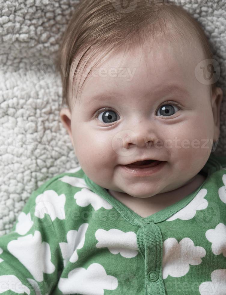 söt liten bebis spelar med händer och leende foto