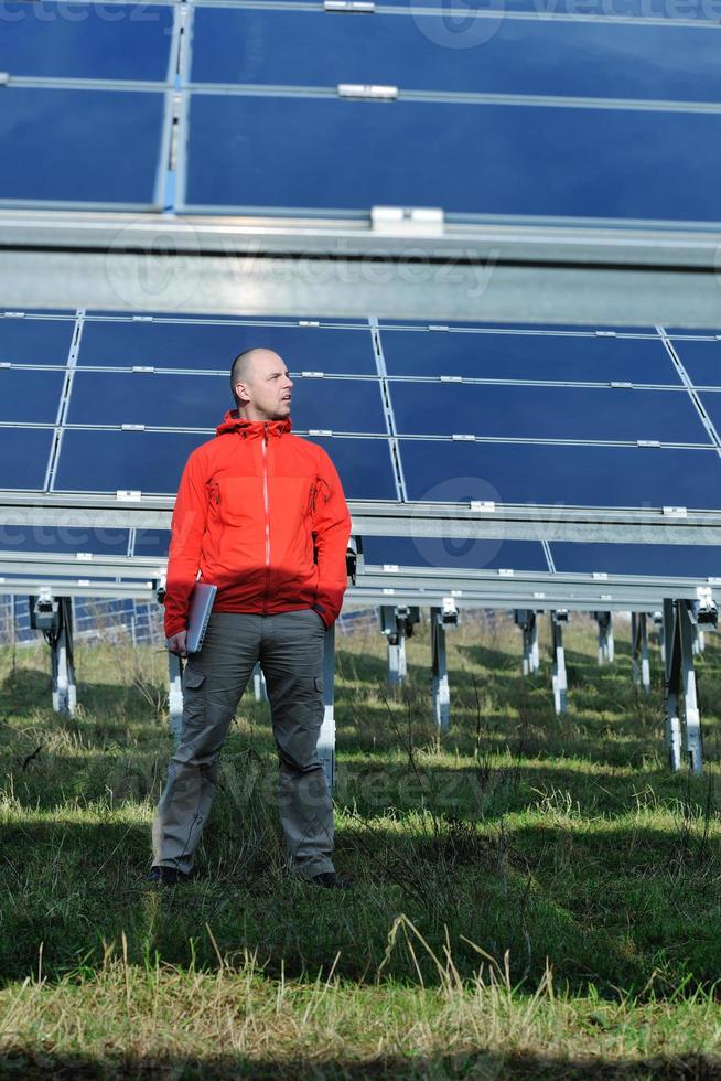 ingenjör använder sig av bärbar dator på sol- paneler växt fält foto