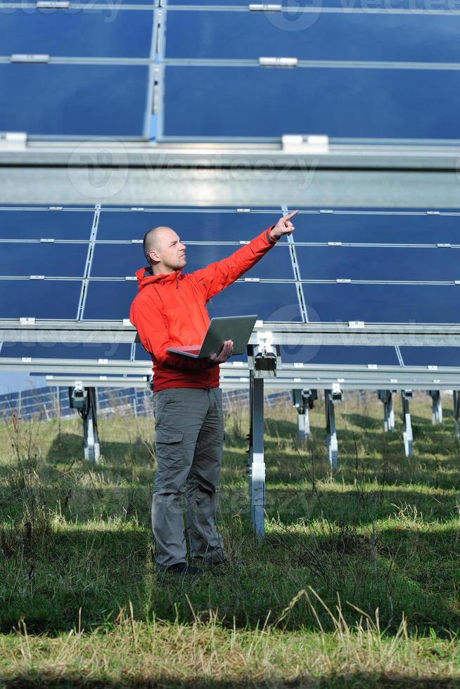 ingenjör använder sig av bärbar dator på sol- paneler växt fält foto