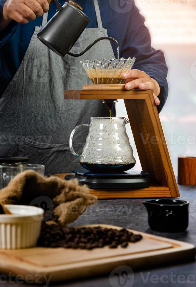 kaffe droppa tillverkare. Barista häller varm vatten över kaffe med papper filtrera foto