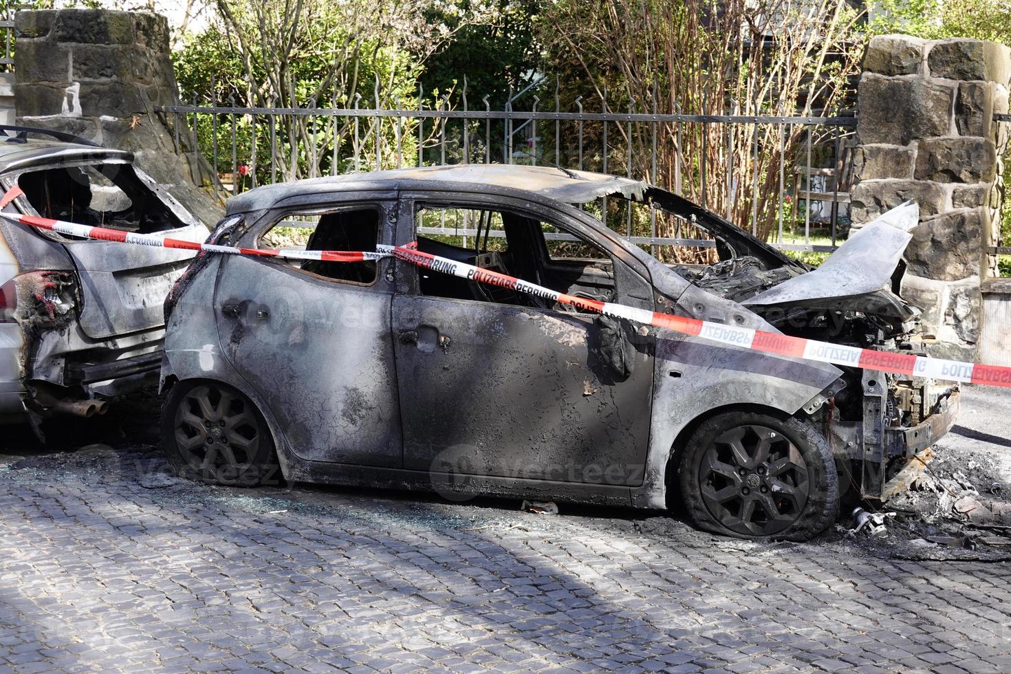 bränd ut bil vrak Bakom polis tejp i bostads- gata i Tyskland foto