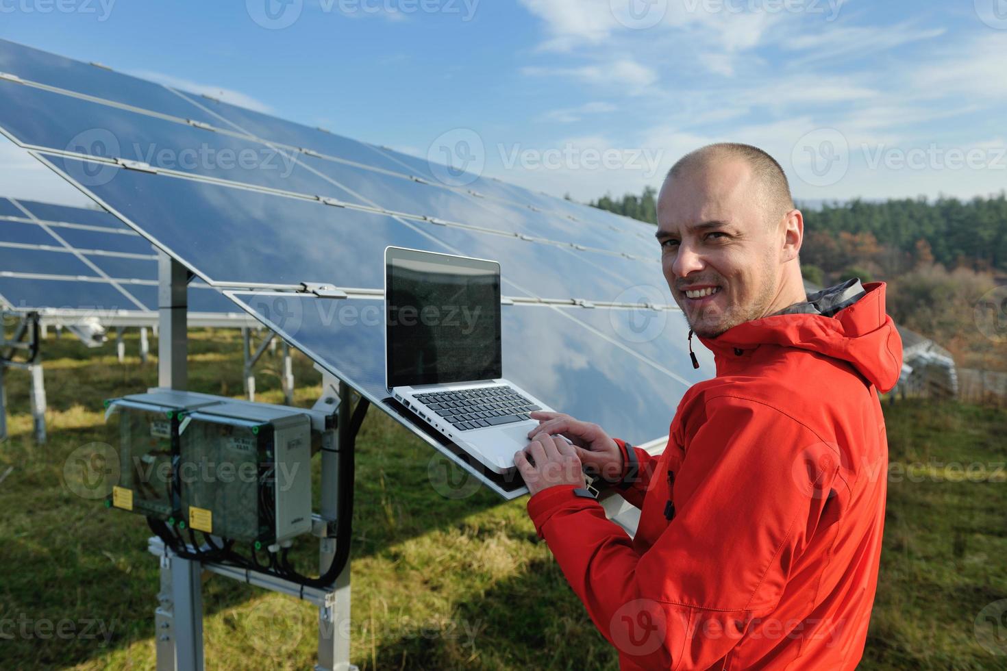 ingenjör använder sig av bärbar dator på sol- paneler växt fält foto