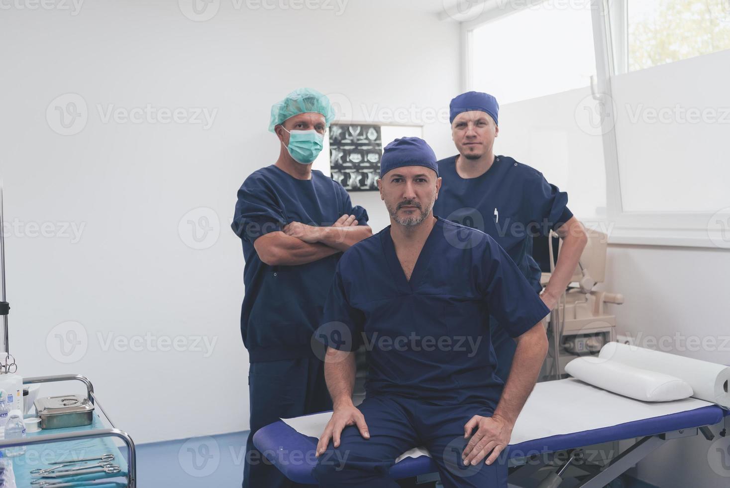 multietnisk ortopedisk läkare i främre av hans medicinsk team ser på kamera bär ansikte mask foto