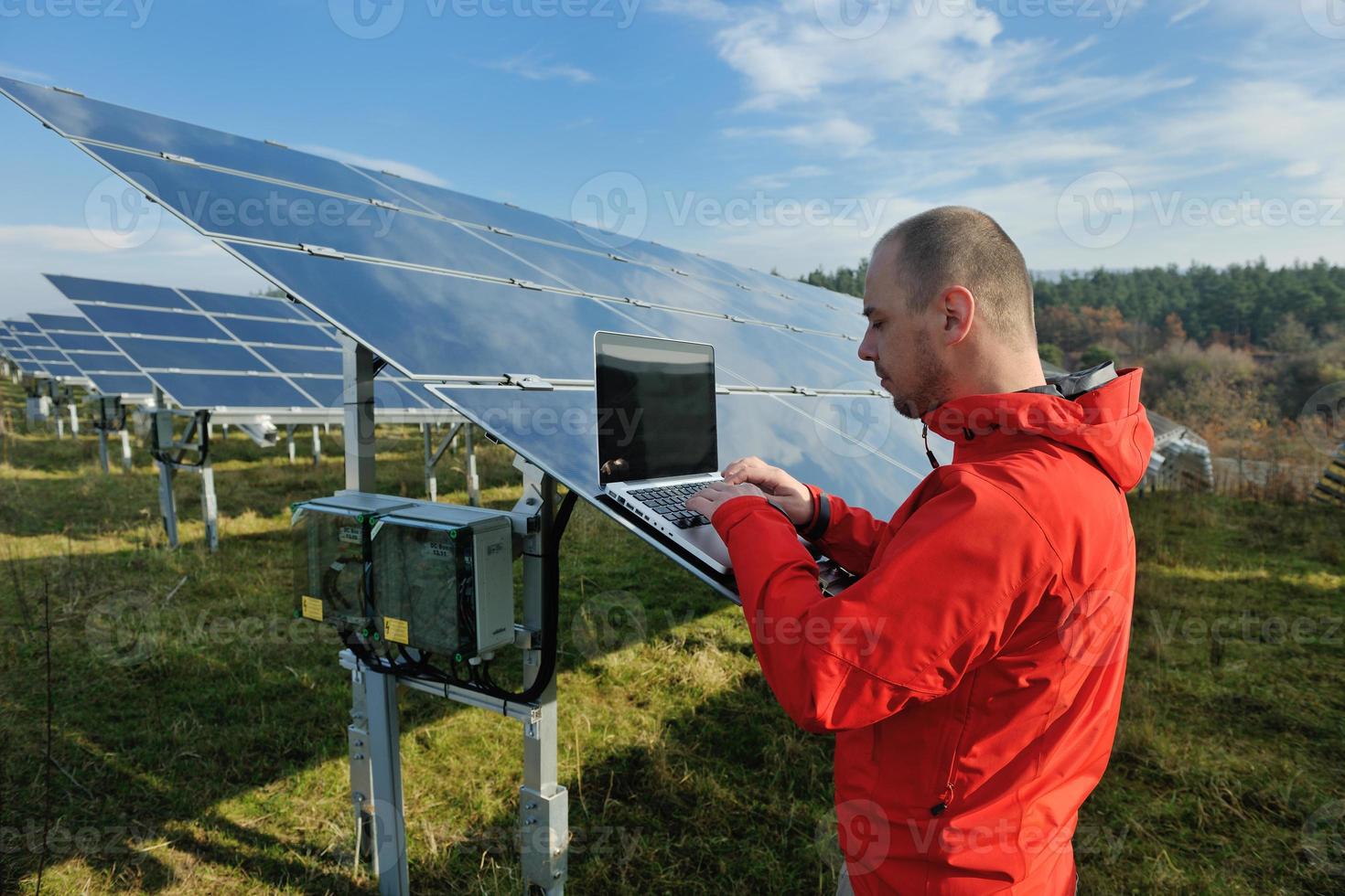 ingenjör använder sig av bärbar dator på sol- paneler växt fält foto