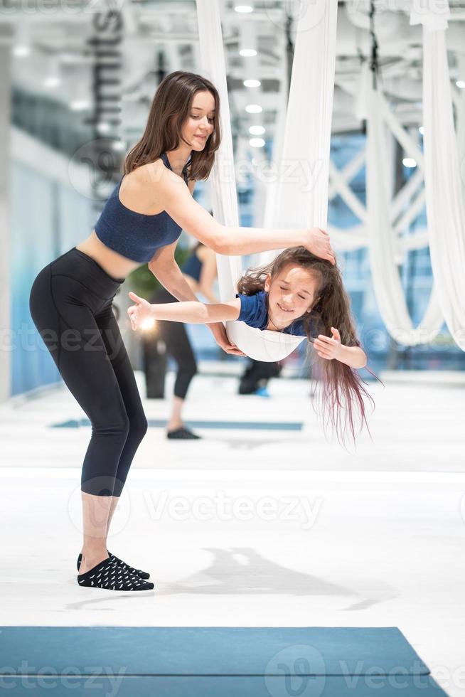 mamma och dotter är håller på med yoga. familj i en Gym. foto