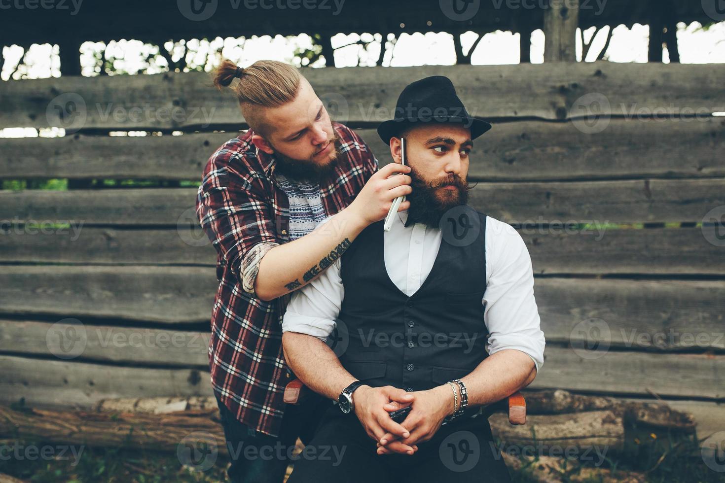 barberare rakar en skäggig man i vintage atmosfär foto