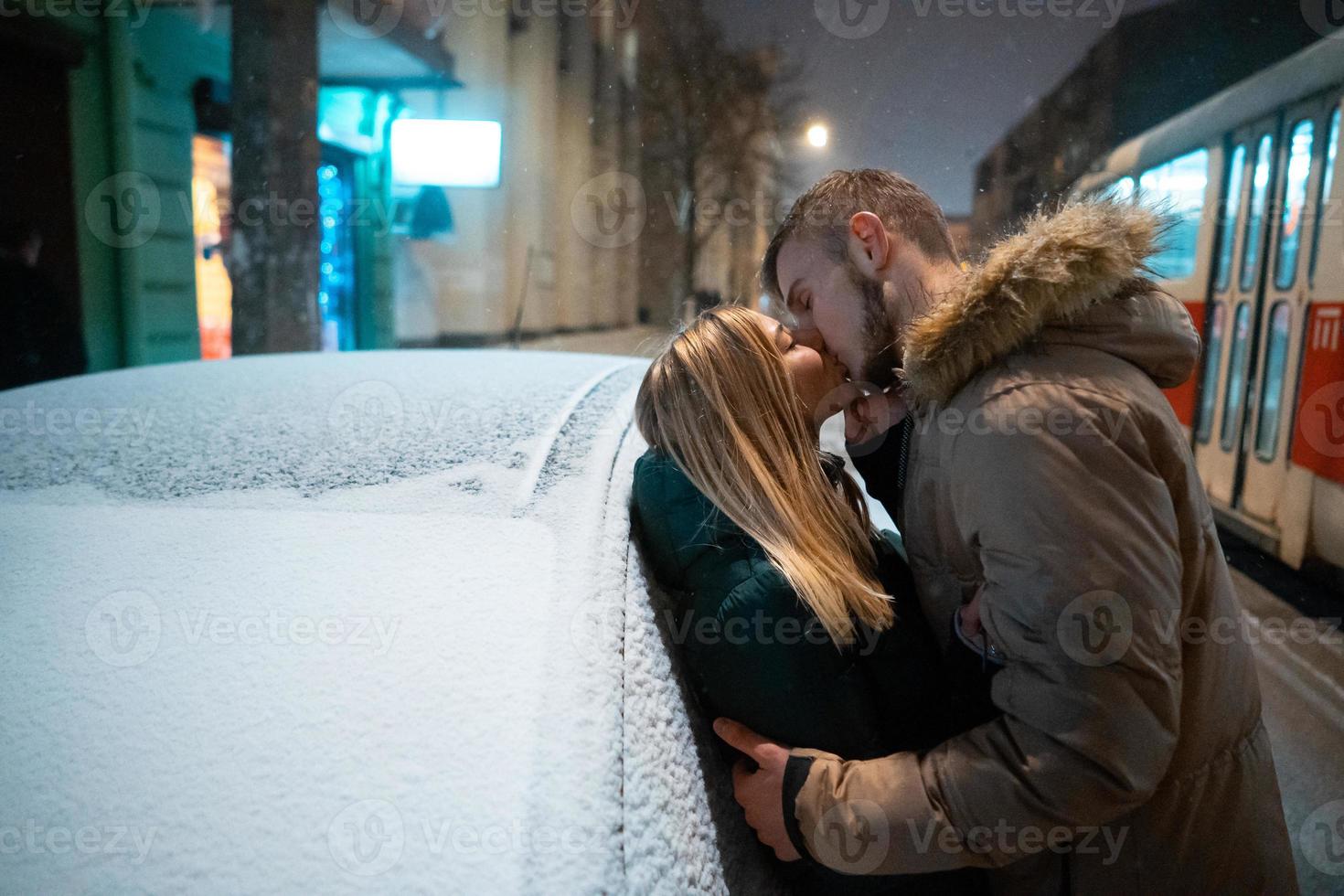 ung vuxen par kissing varje Övrig på snö täckt gata foto