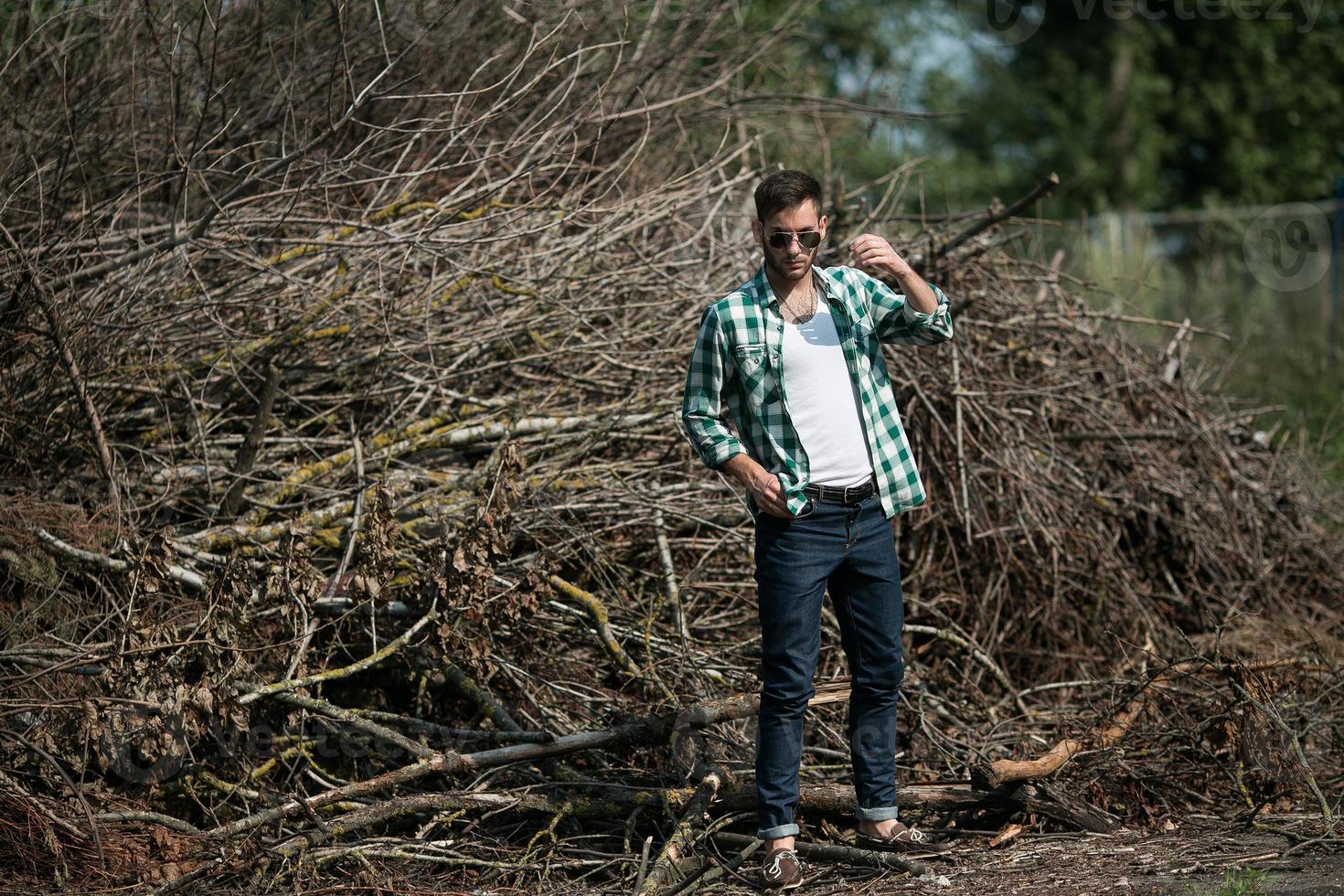 de man i de äkta stövlar och själva kanten jeans på en de bakgrund av grenar foto