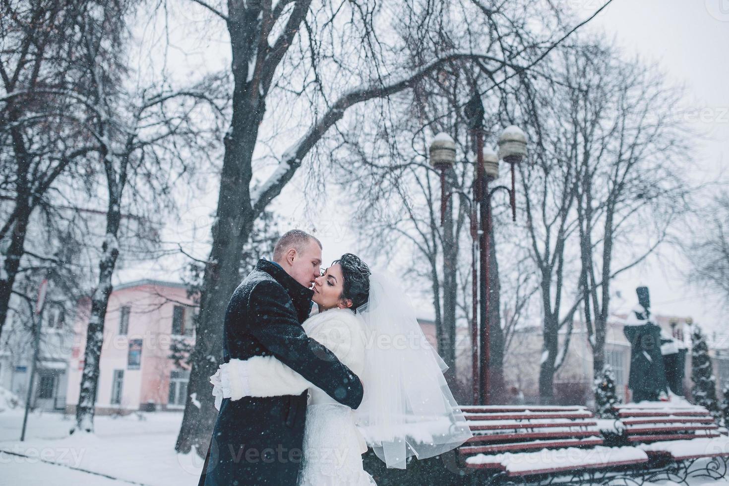 bruden och brudgummen går på den europeiska staden i snön foto