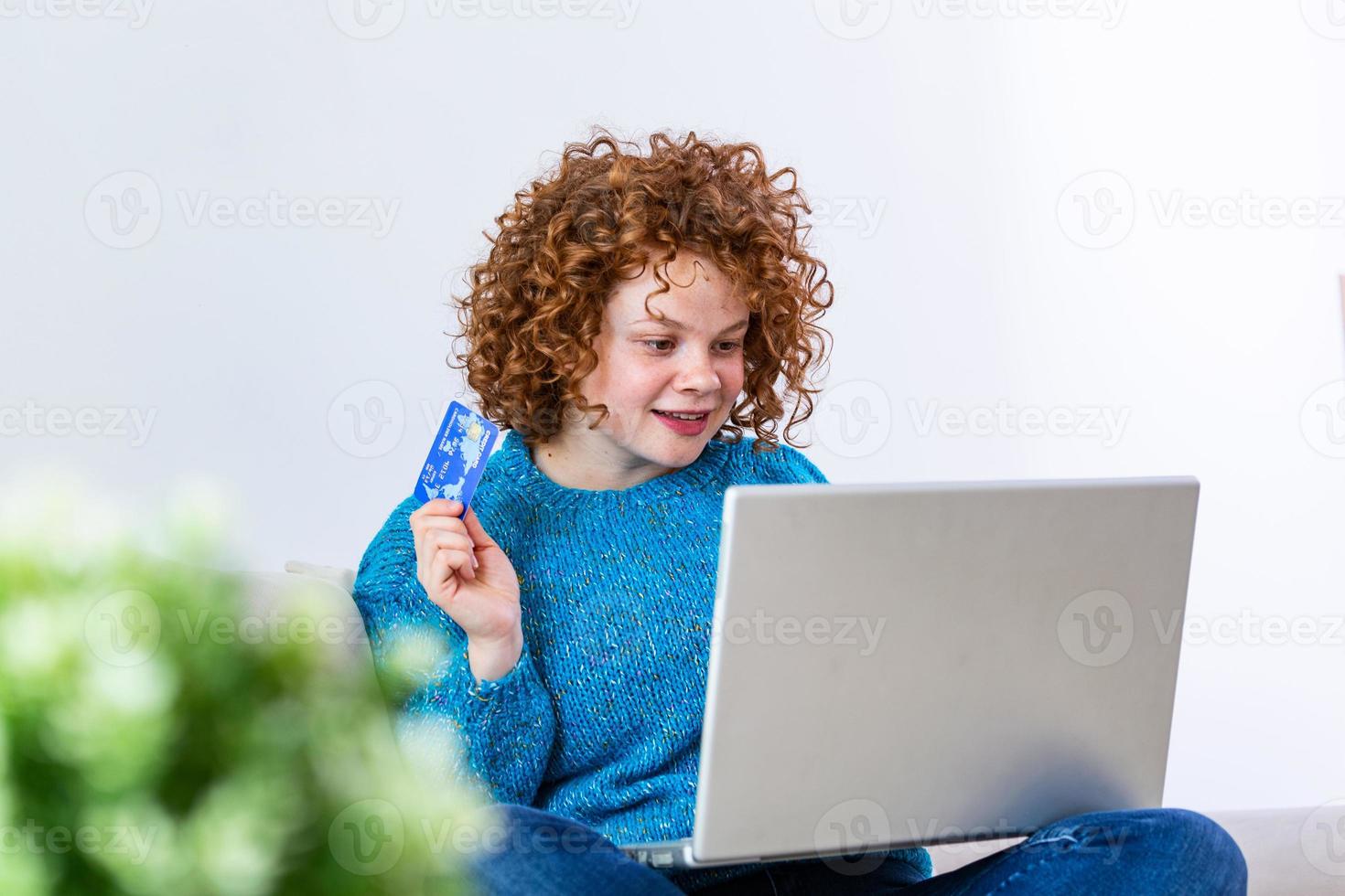 söt röd hår kvinna handla uppkopplad med kreditera kort. kvinna innehav kreditera kort och använder sig av bärbar dator. uppkopplad handla begrepp foto