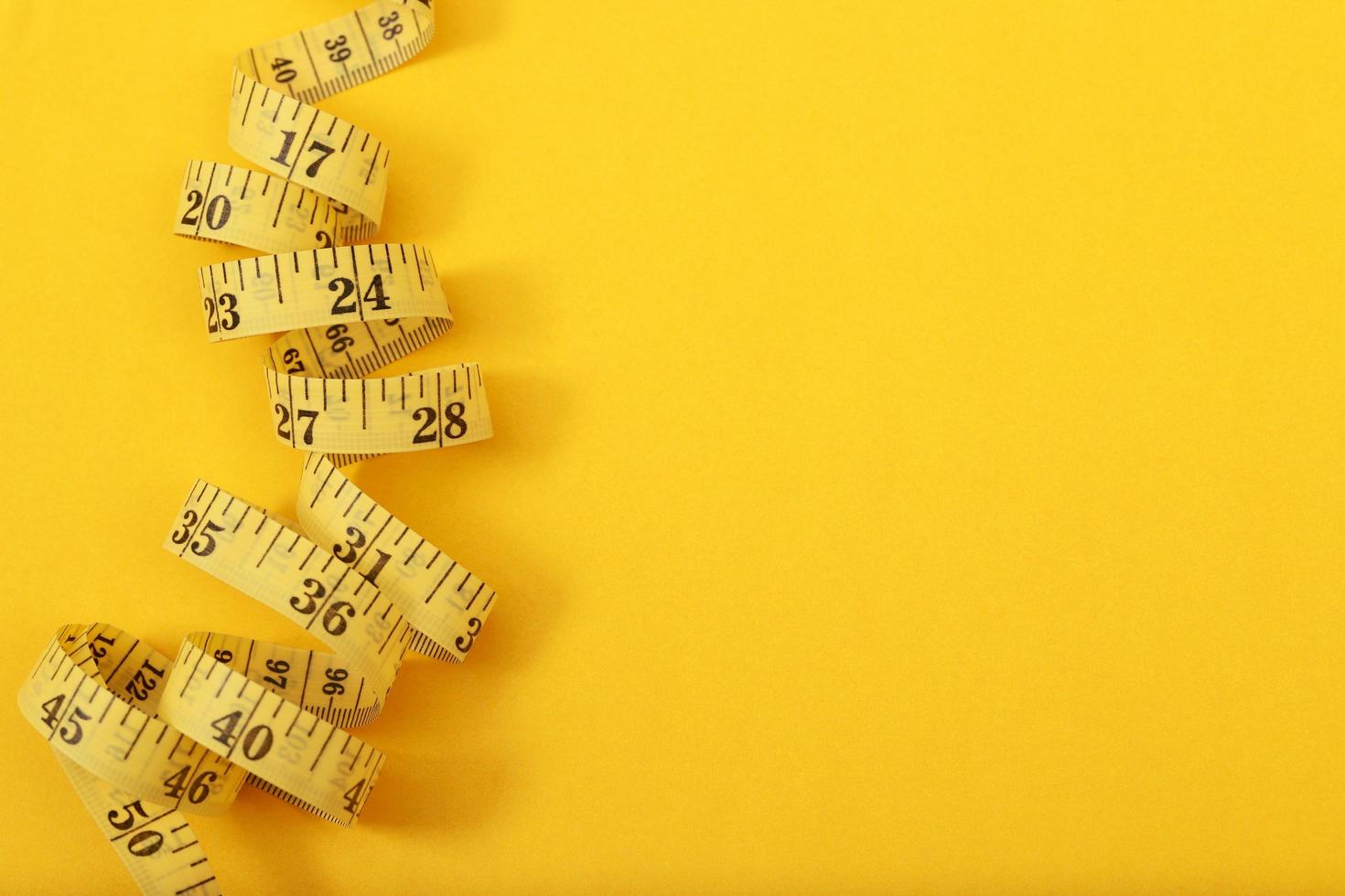 tejp mäta för fet människor på en gul bakgrund mjuk fokus foto