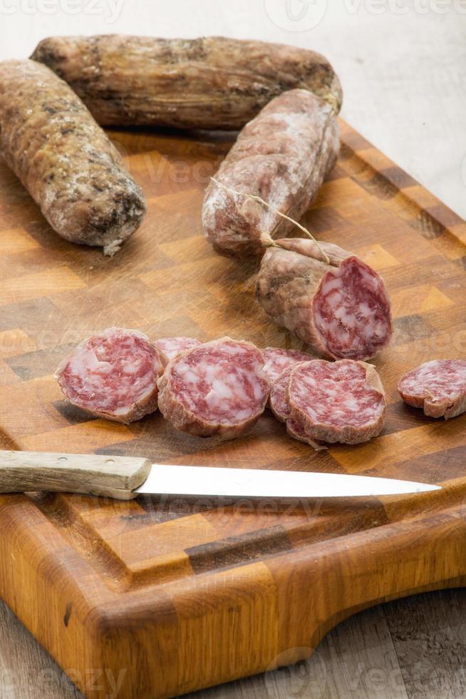 italienska salamiskivor på skärbräda med kökskniv foto
