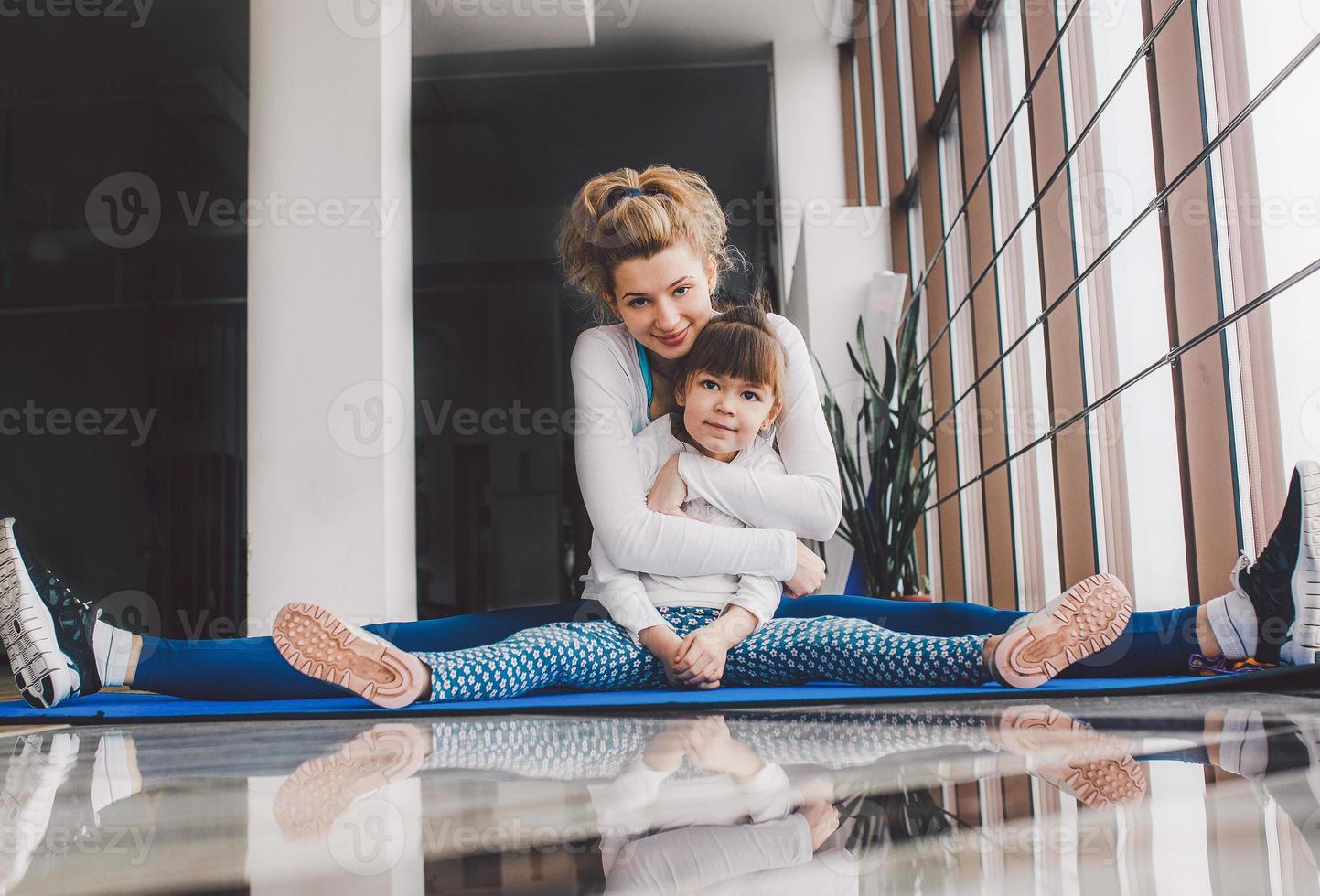 mor och dotter kramar och sträcka i de Gym foto