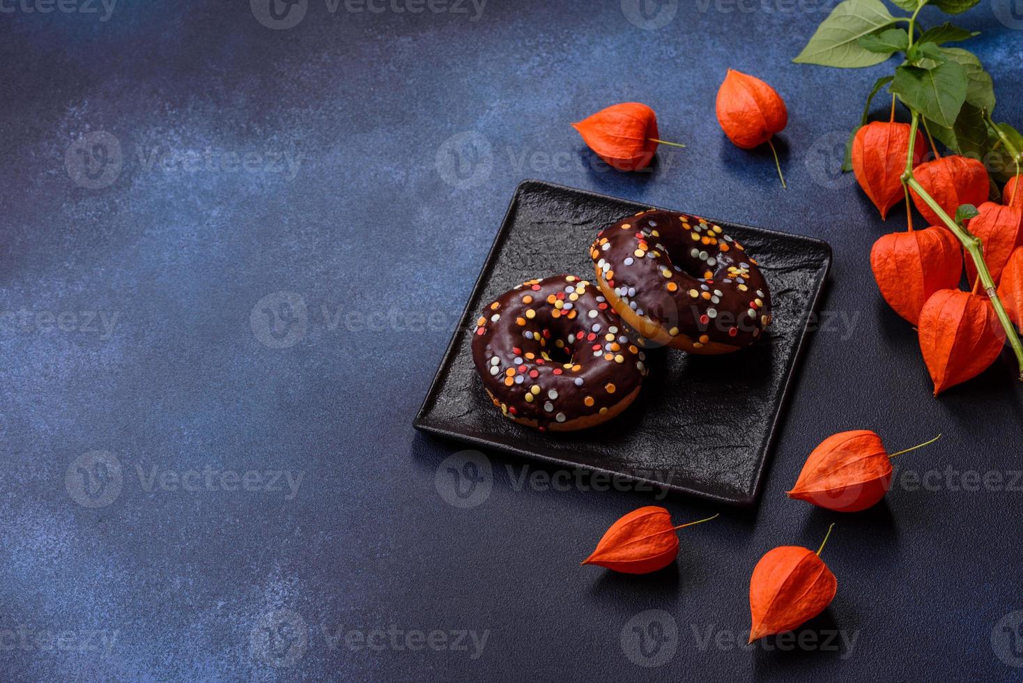 bakverk begrepp. munkar med choklad glasyr med strössel, på en mörk betong tabell foto