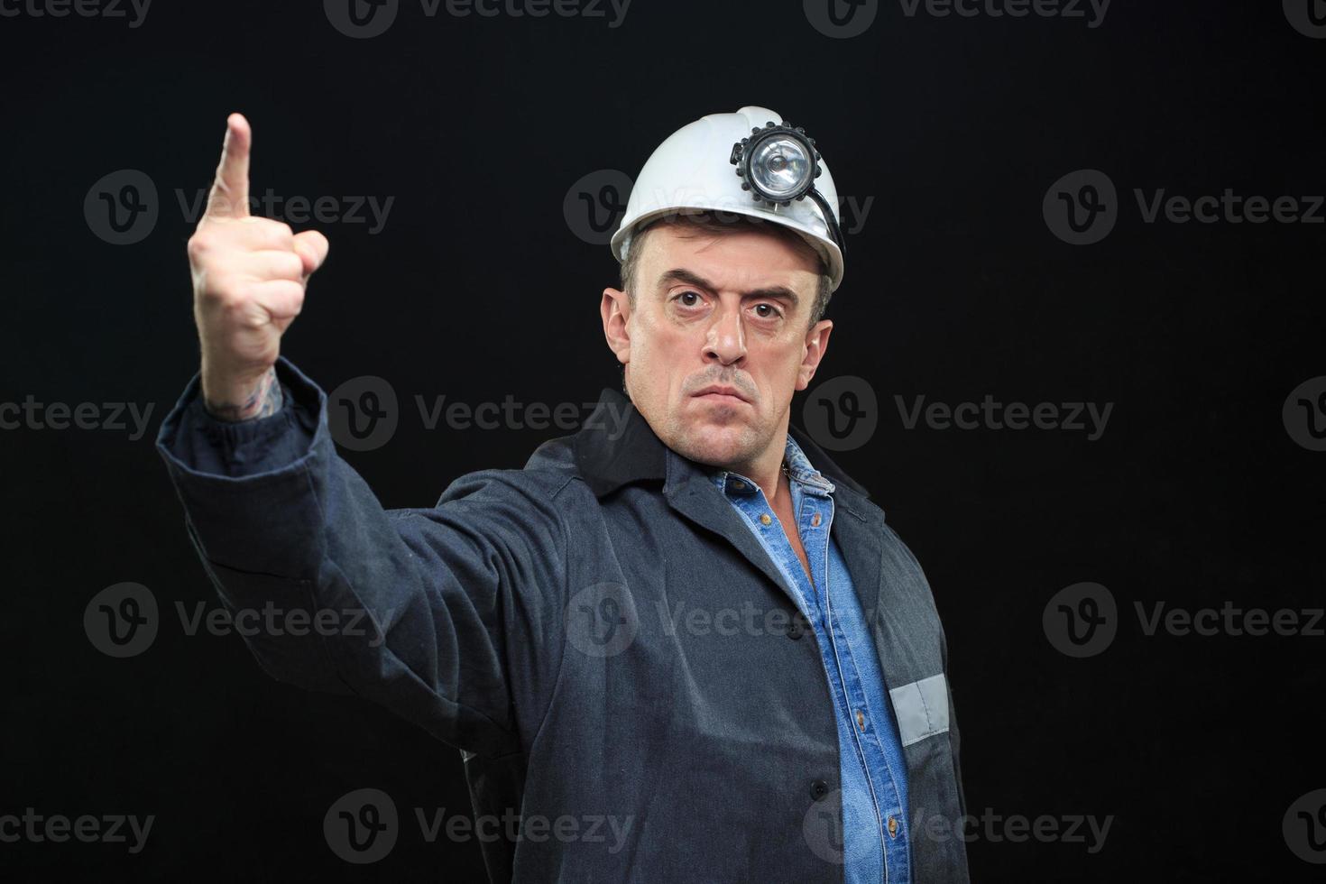 man med kol gruvarbetare hatt och säkerhet kläder pekar finger foto