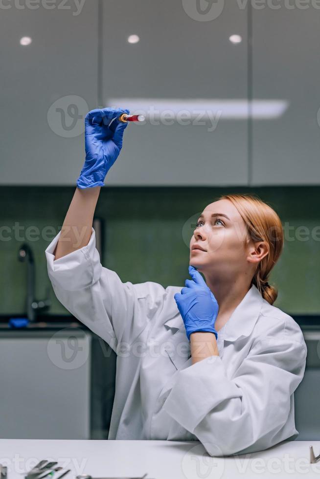 kvinna medicinsk eller vetenskaplig forskare ser på en testa rör i en laboratorium. foto