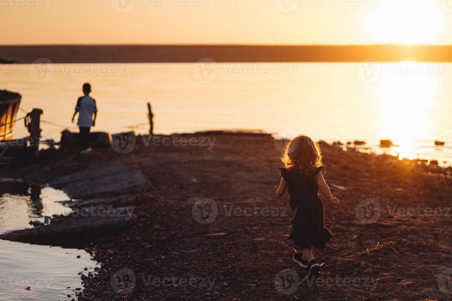 två barn promenad längs de strand, sommar kväll foto