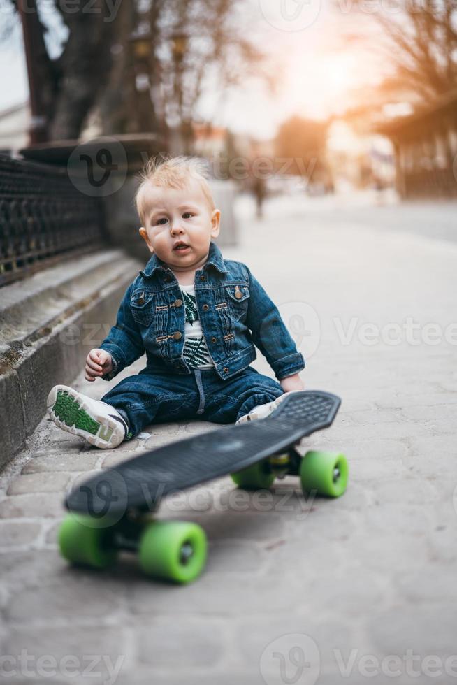 liten rolig pojke med skateboard på de gata foto