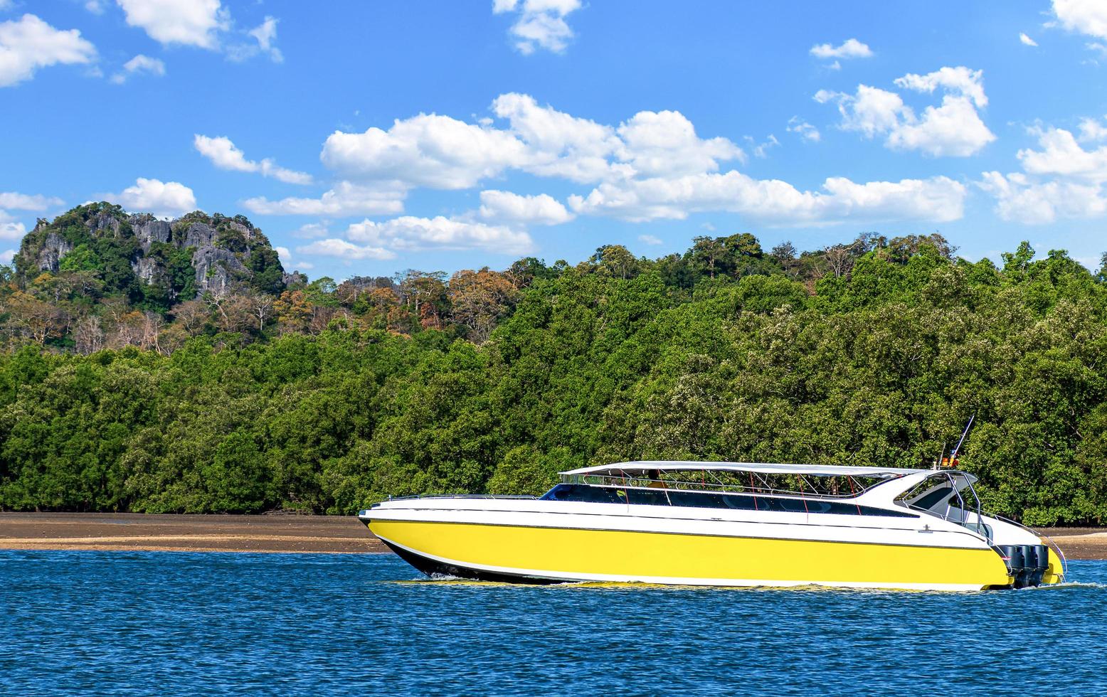 de gul hastighet båt på hav med blå himmel och berg bakgrund foto