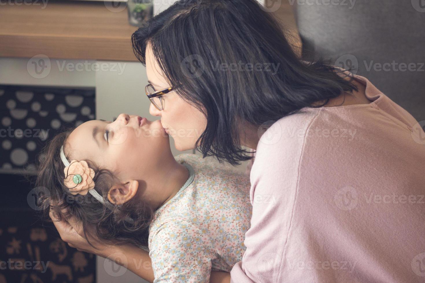 kärleksfull mor kissing henne små dotter. foto