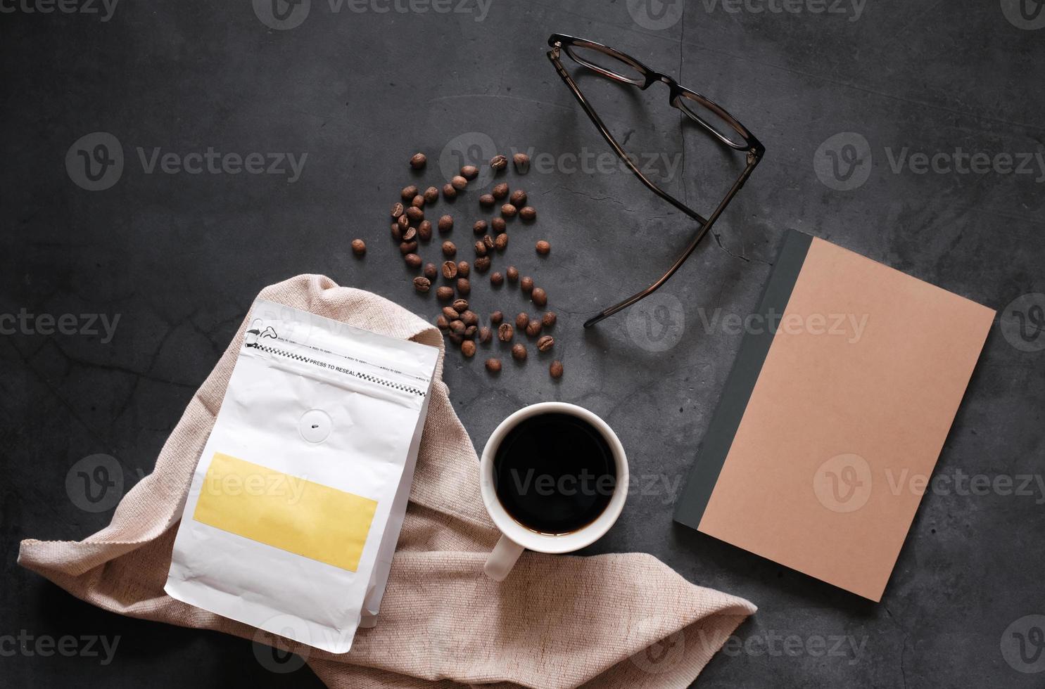 branding identitet av kaffe bönor och varm kopp av svart kaffe dryck med tom anteckningsbok på sten bakgrund, företag och attrapp begrepp foto