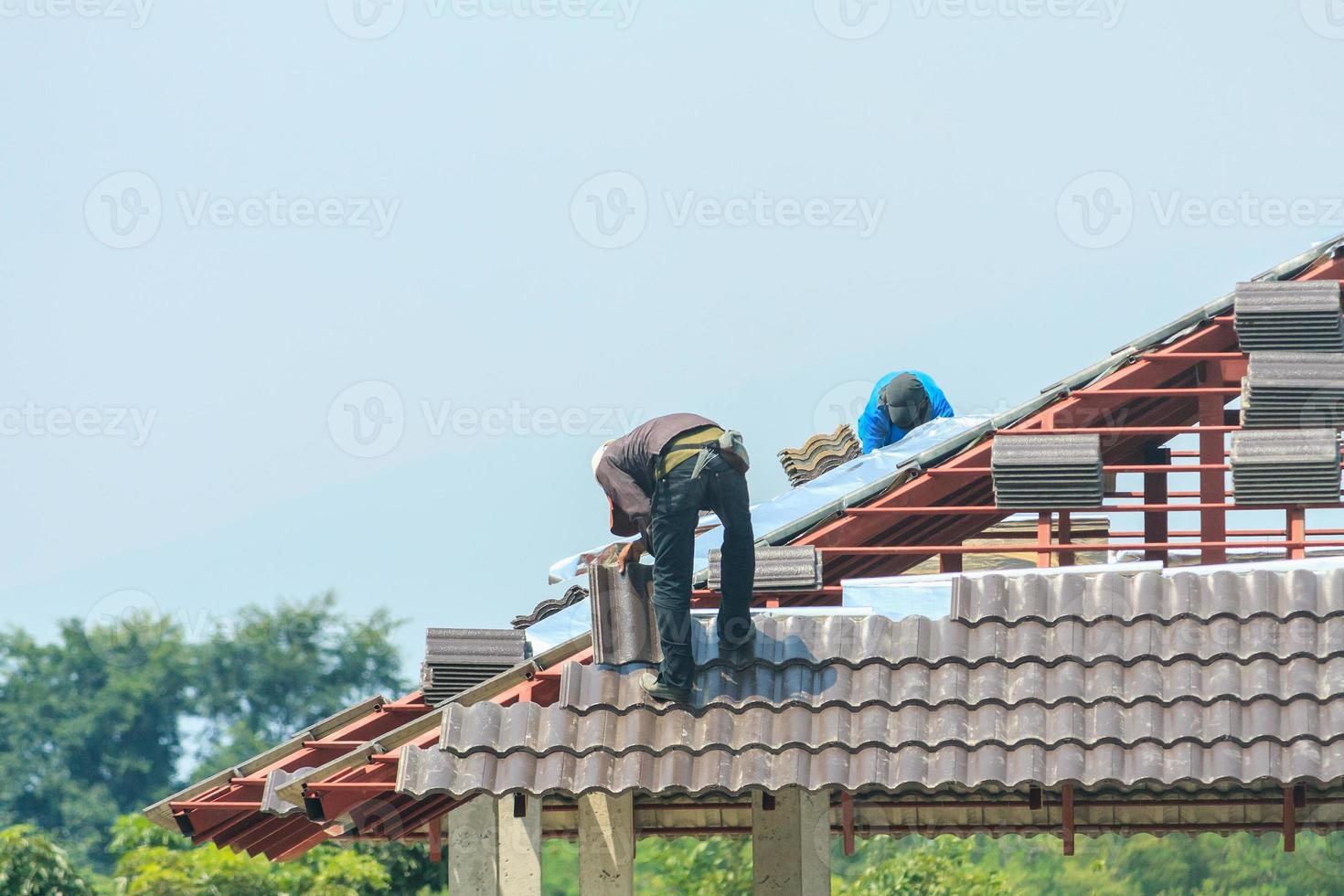 byggtäckare som installerar takpannor på husbyggarbetsplatsen foto