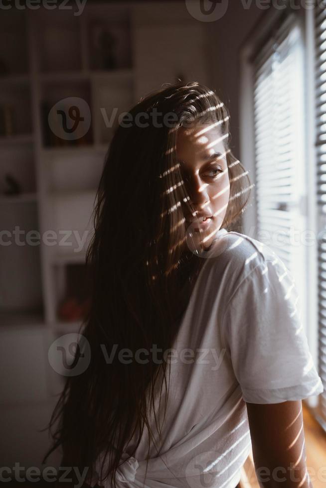 ung kvinna nära de fönster i de morgon- foto