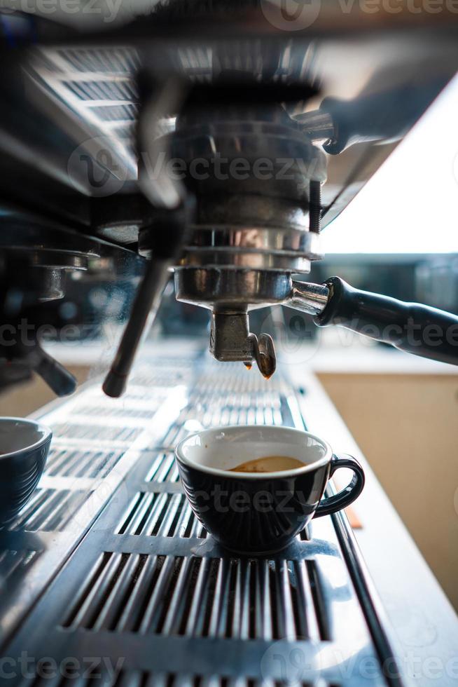 liten kopp av espresso stående i de stål kaffe maskin foto