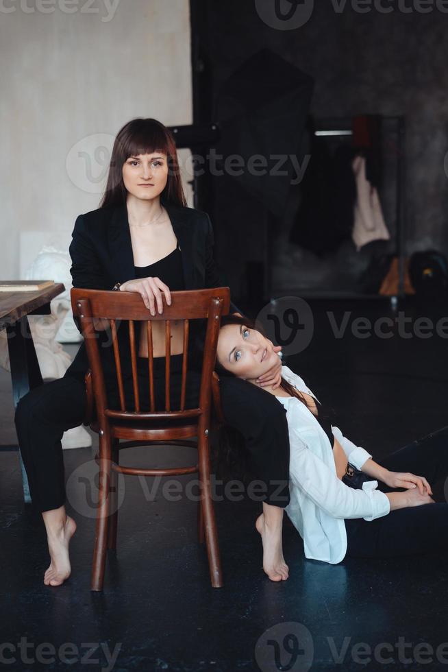 två flickor är Framställ för de kamera, ett Sammanträde på en stol, Övrig på de golv foto