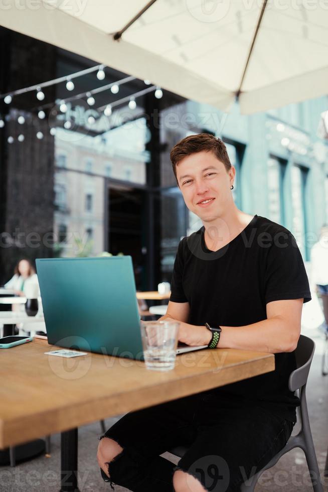 porträtt av man Sammanträde på en tabell arbetssätt på en bärbar dator dator. foto