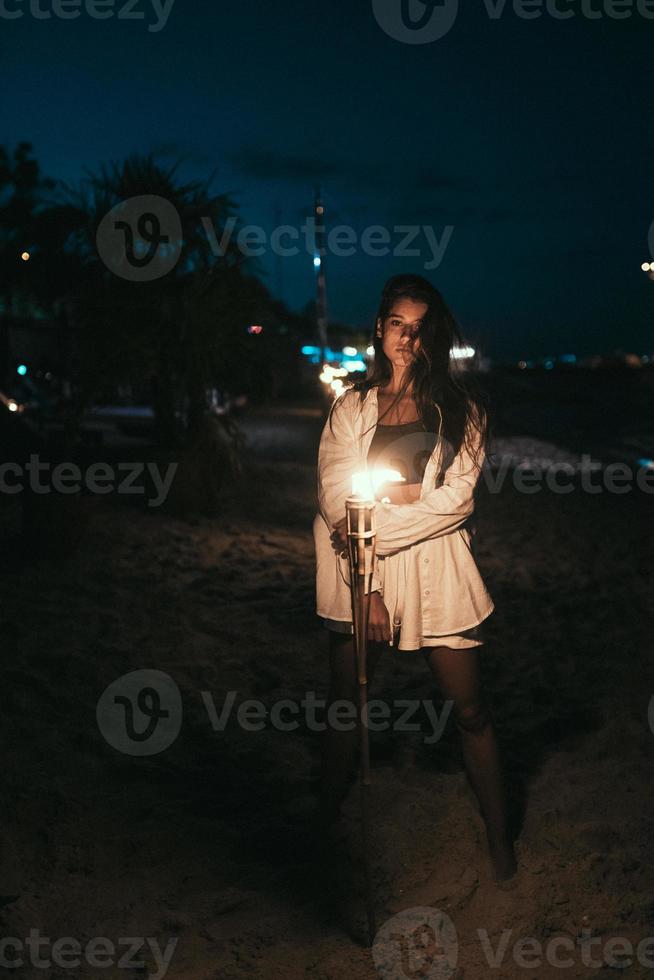ung kvinna med fackelsken på de strand på natt foto