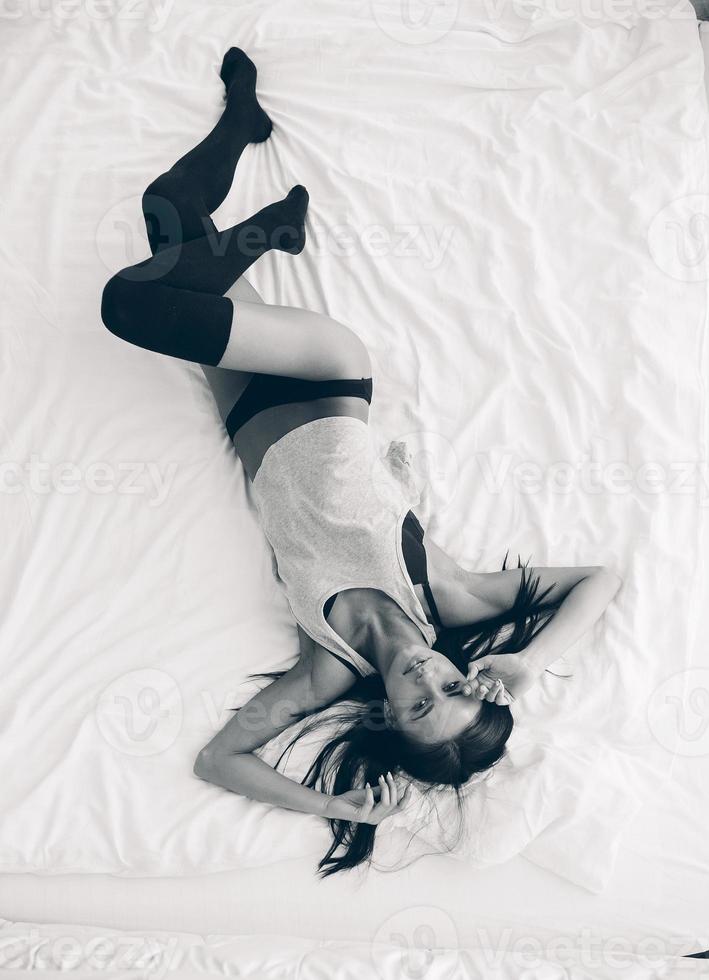 skön ung flicka Framställ på en vit säng foto