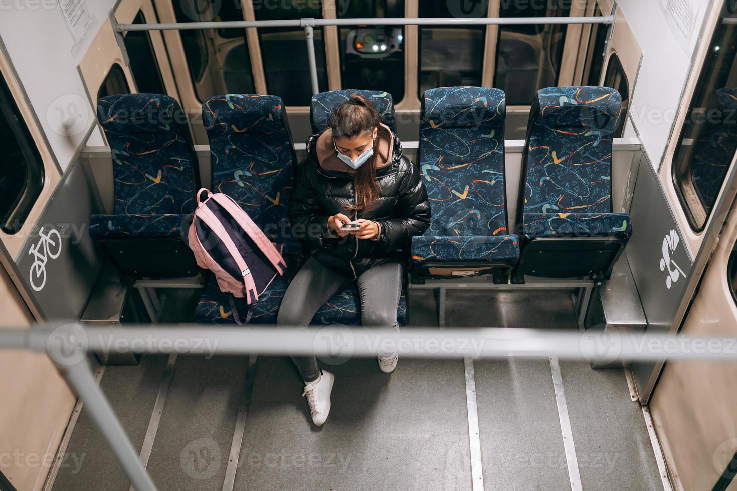 ung kvinna med mask reser i de offentlig transport. foto