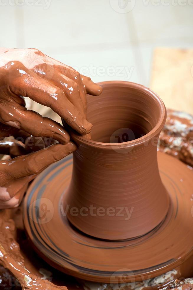 händerna på en keramiker som skapar en lerkrukan foto