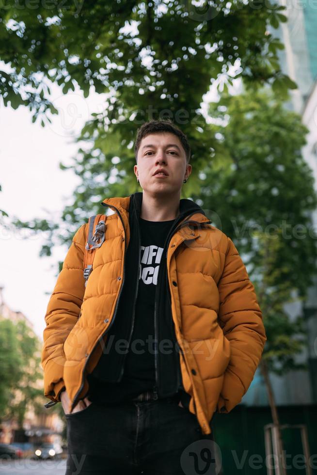 ung vuxen man i en gul jacka och jeans promenader på en stad gata foto