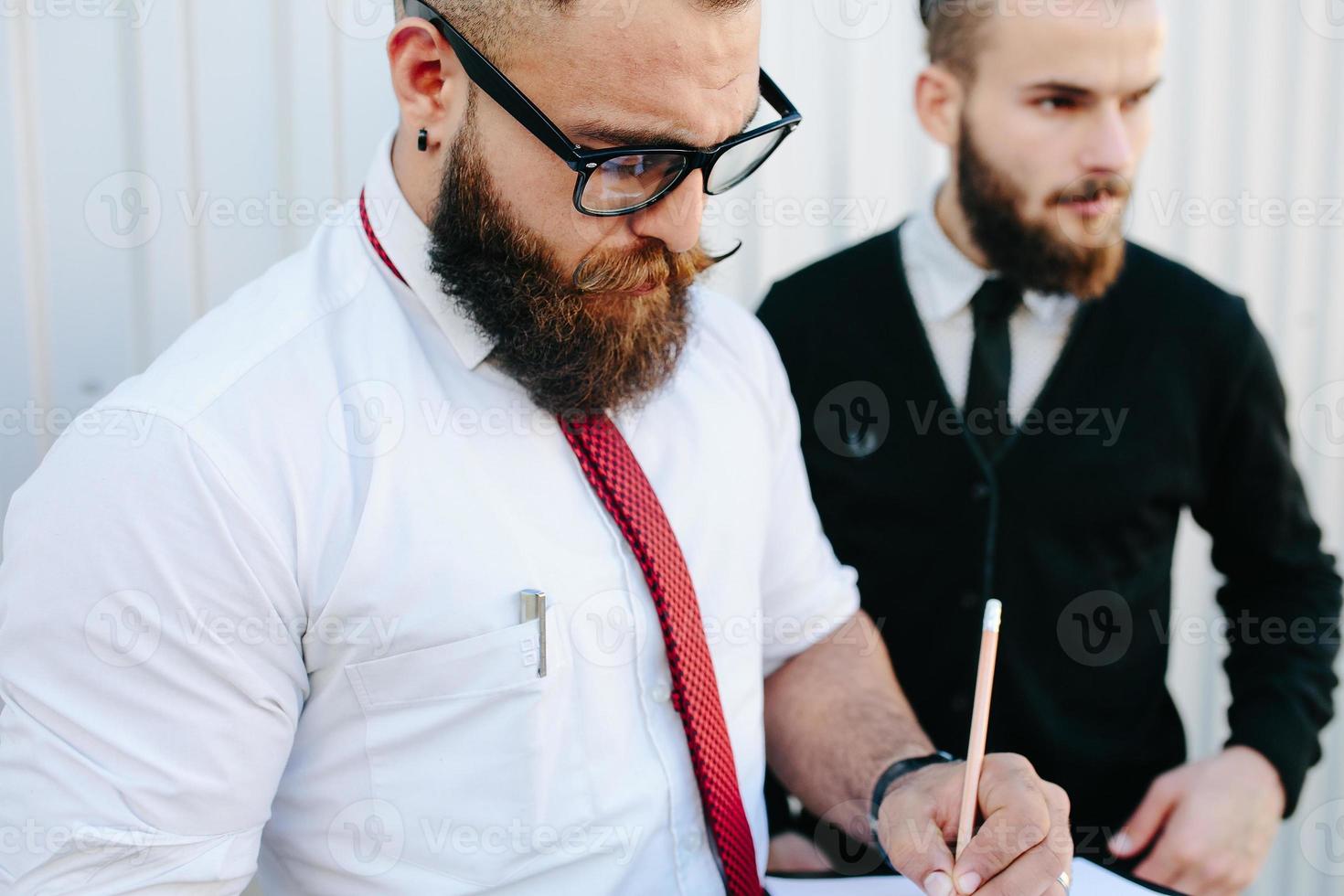 två skäggig affärsman signering dokument foto