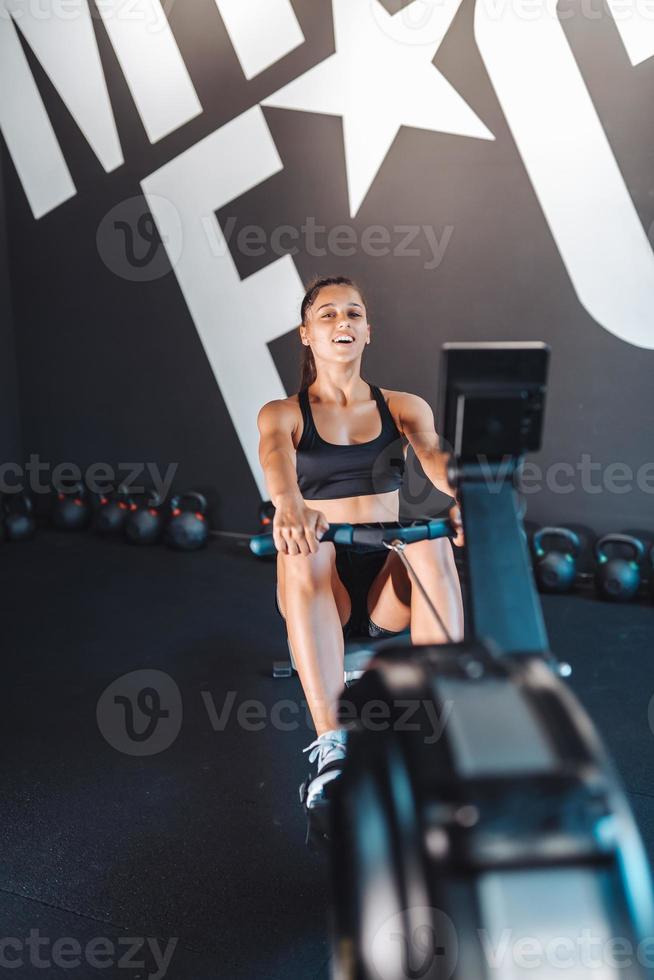 ung kvinna Träning och dragande vikter i sittande kabel- rad maskin. foto