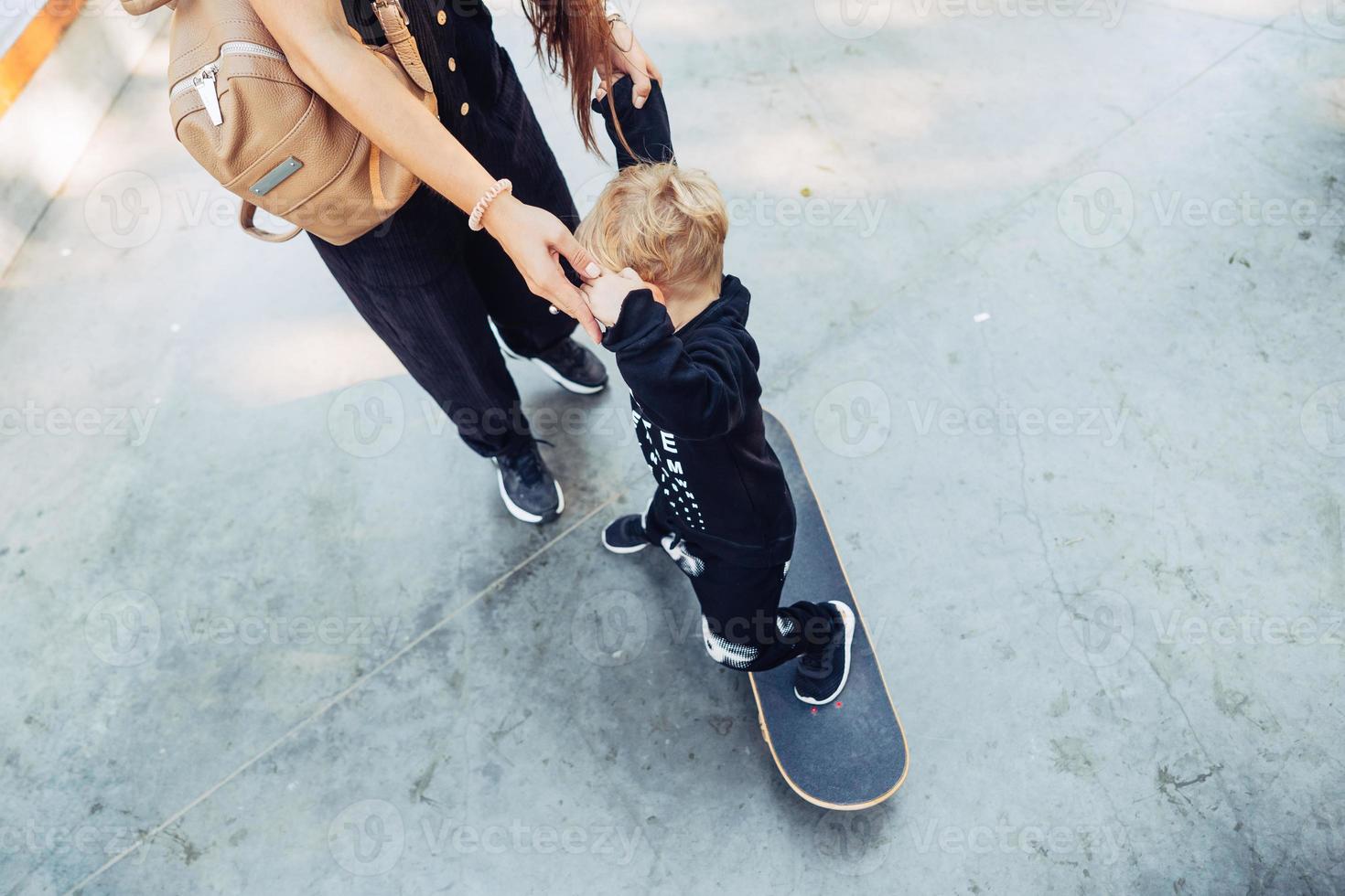 ung mor lär henne liten pojke till rida en skateboard foto