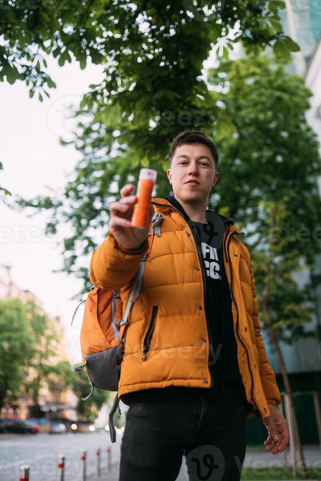 ung vuxen man i en gul jacka och jeans promenader på en stad gata foto