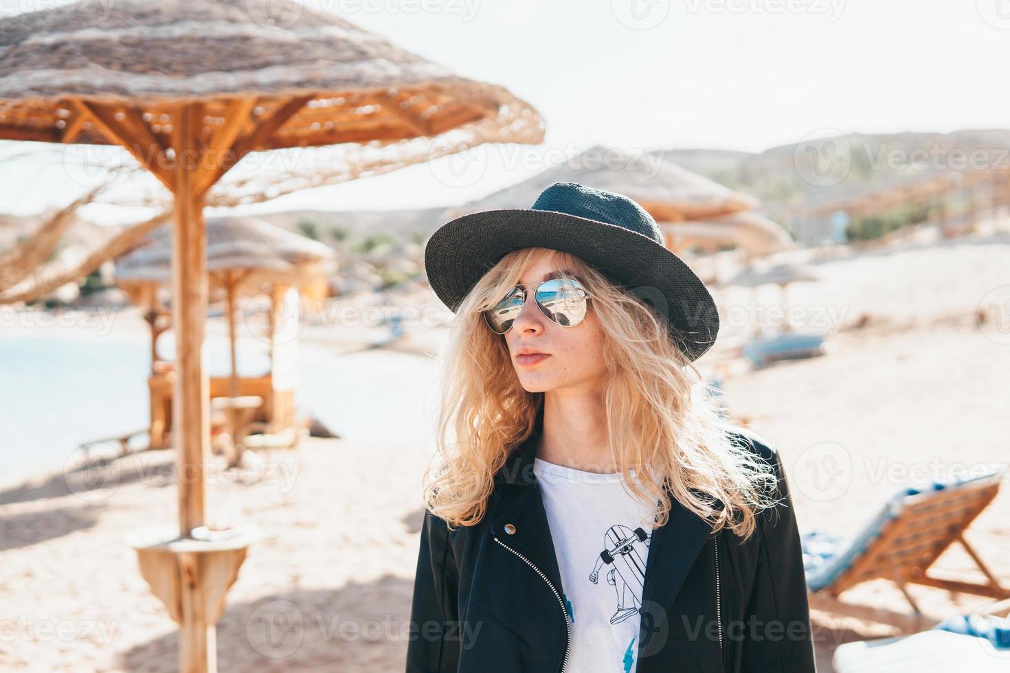 ung kvinna i sugrör hatt och solglasögon på strand foto