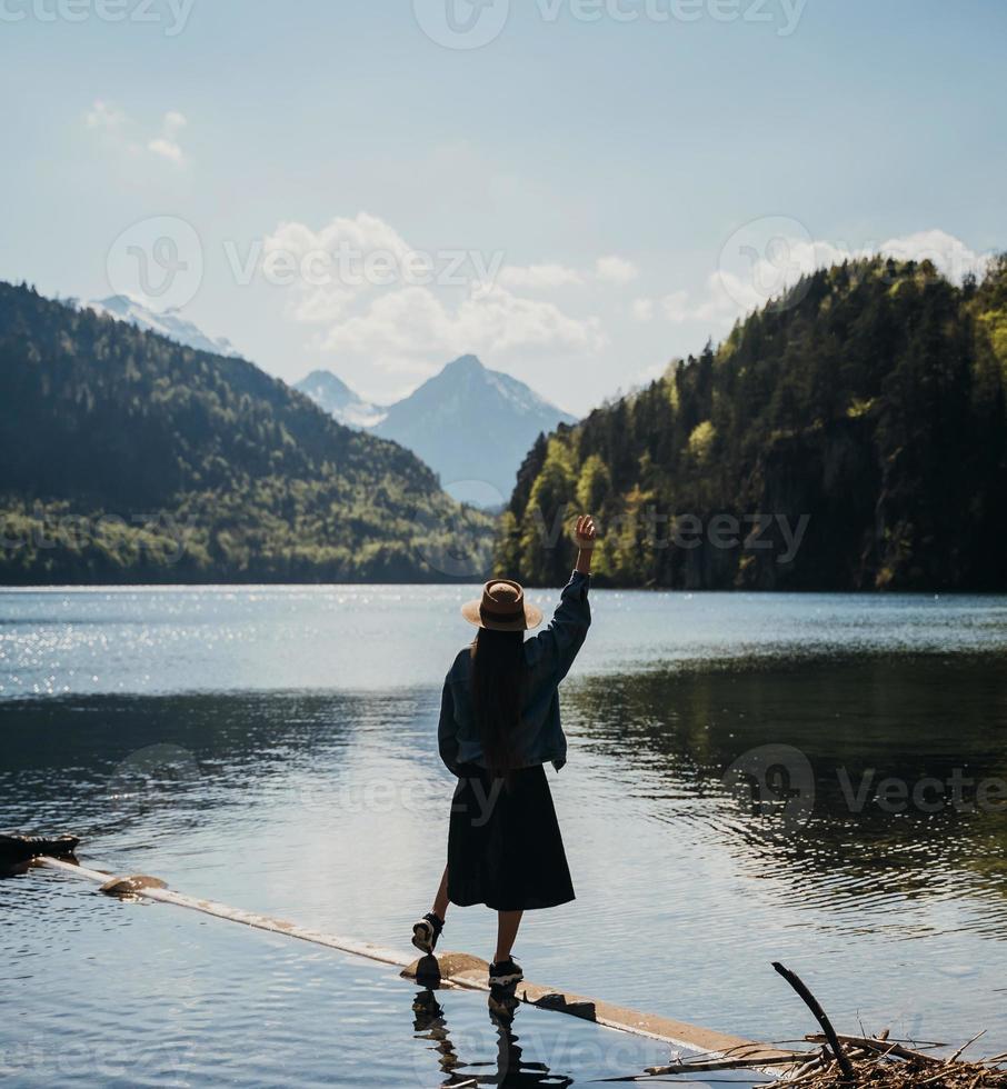 de flicka i de klänning och hatt av de sjö i de bergen foto