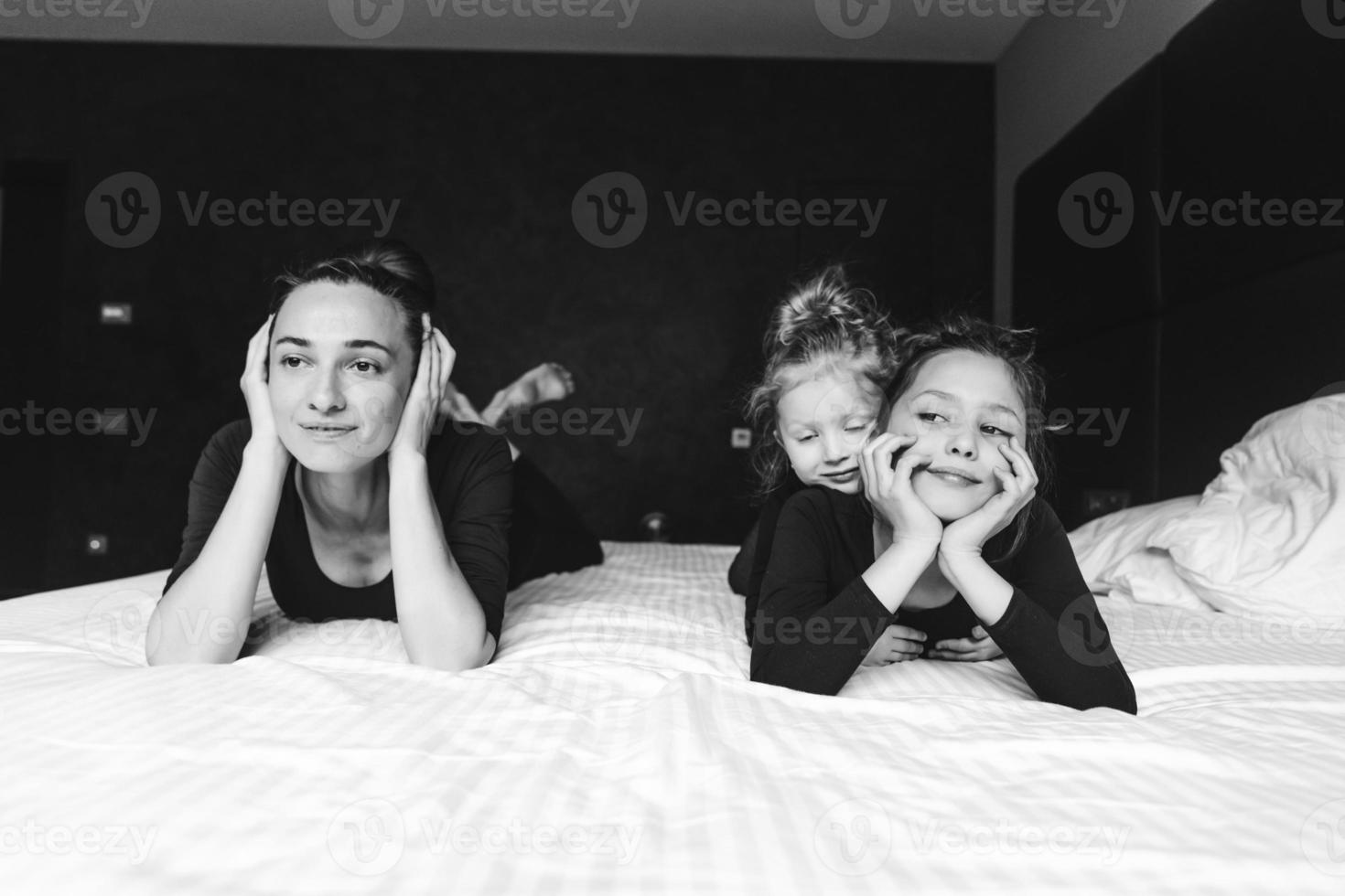 mamma och två döttrar ha roligt på de säng foto