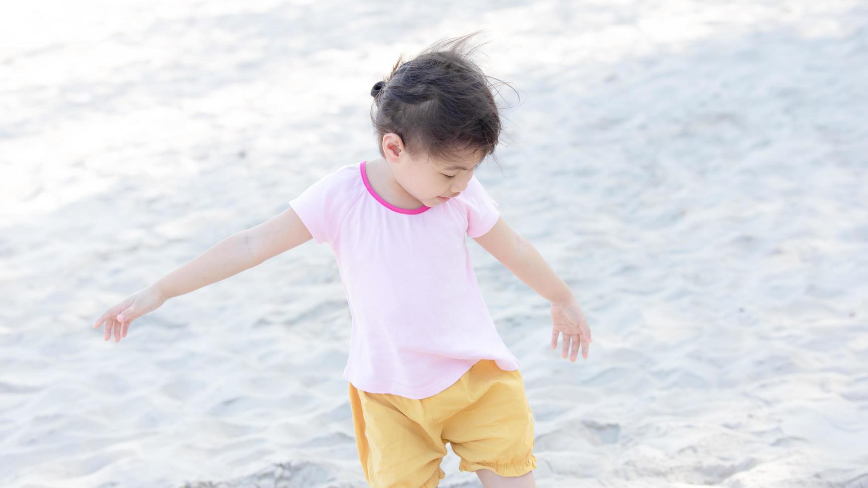 positiv charmig 4 år gammal söt bebis asiatisk flicka, litet förskolebarn som leker på sandstranden på vacker solig dag på sommaren foto