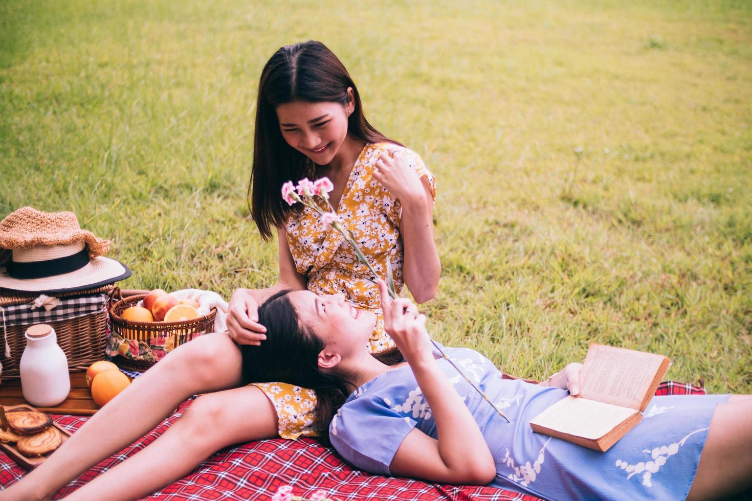 två kvinna vänner njuter picknick tillsammans i en parkera. foto