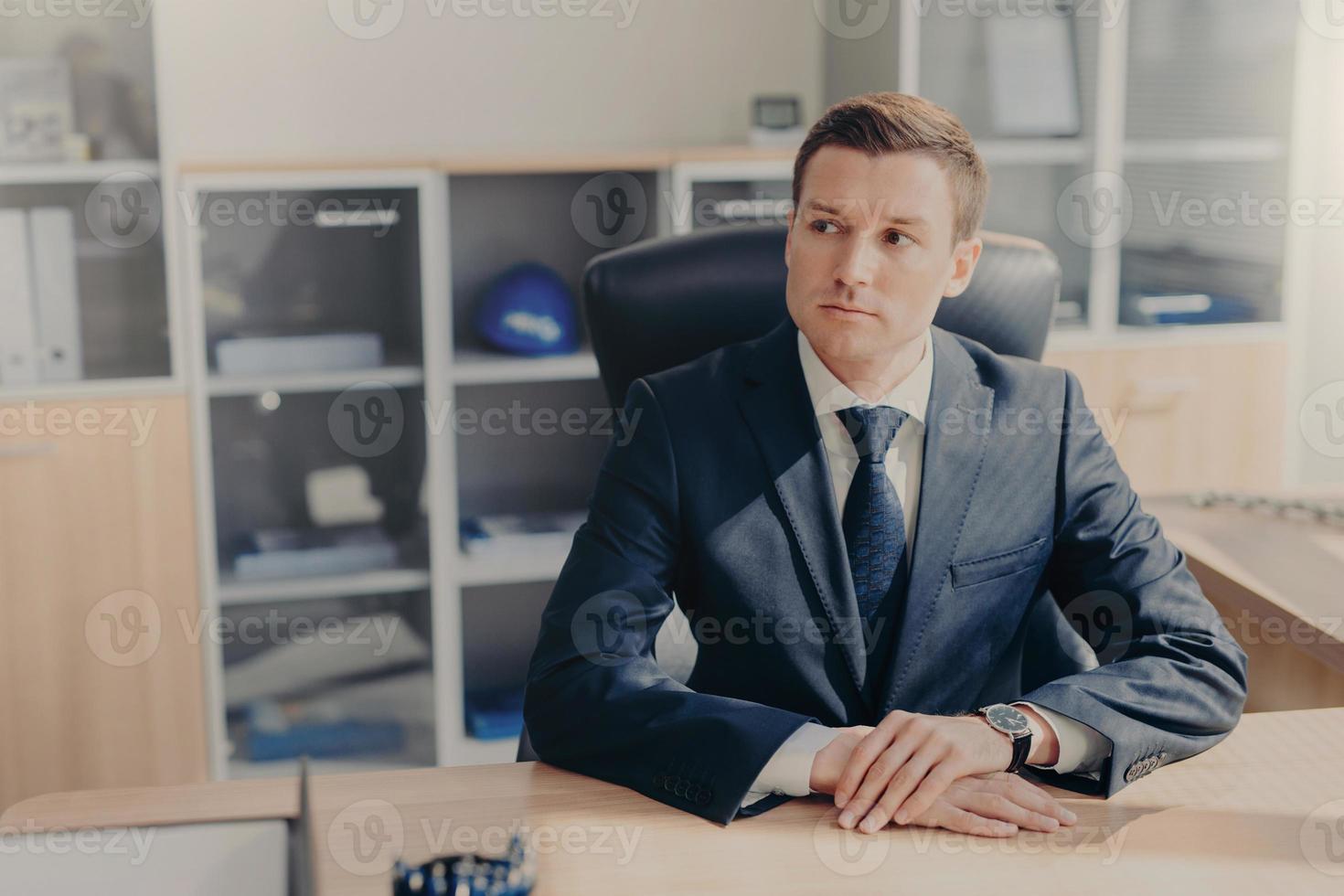 porträtt av omtänksam affärsman i elegant kostym sitter på kontoret vid sitt skåp, funderar på att skapa en ny affärsplan, funderar på strategier för att öka försäljningen, ska ha arbetsuppehåll i restaurangen foto