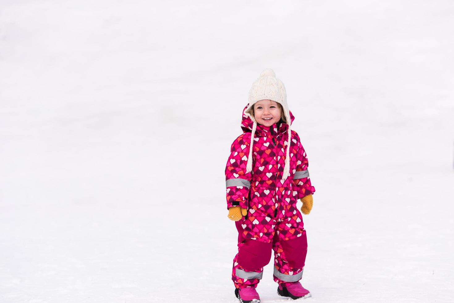 liten flicka har roligt på snöig vinter- dag foto